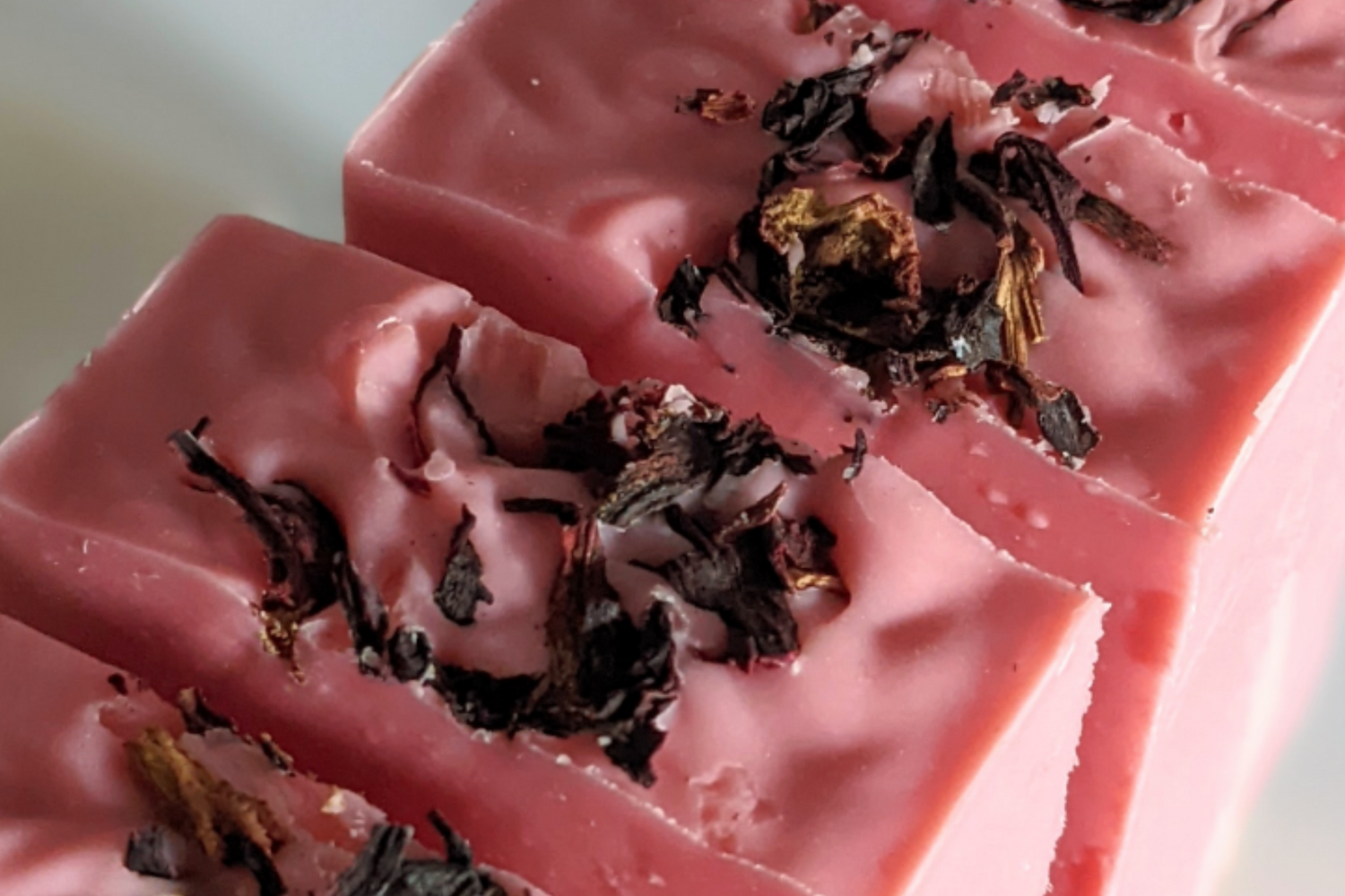 Pink soap bars with dried herbs on a light background